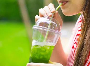 woman sipping iced green beverage outside